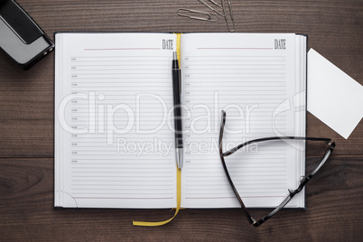 personal organizer and pen with glasses on the table
