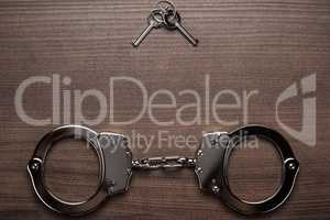 steel handcuffs and keys on the wooden background