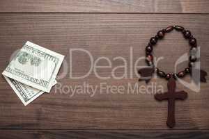 wooden cross and money on brown table background