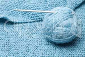 ball of blue wool with grey knitting needle
