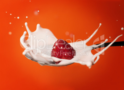 frozen strawberry splashing into yoghurt in the spoon