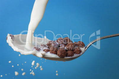milk splashing into spoon with chocolate cornballs