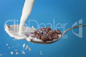 milk splashing into spoon with chocolate cornballs