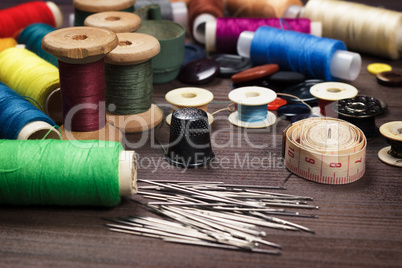 needles buttons and threads on brown wooden table