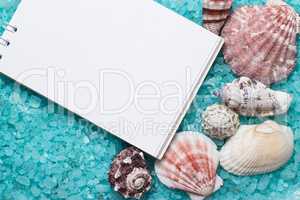 notebook over blue bath salt and seashells background