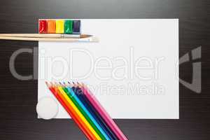 sheet of paper on the brown table with colorful paints and penci