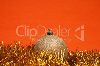 shiny christmas ball with tinsel over orange background