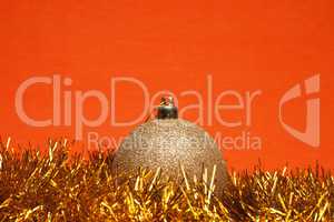 shiny christmas ball with tinsel over orange background