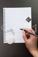 woman writing with pencil on notebook in office