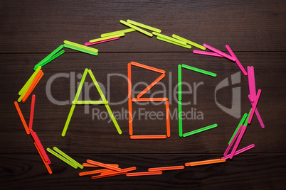 abc letters formed with counting sticks over wooden background