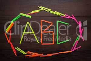 abc letters formed with counting sticks over wooden background