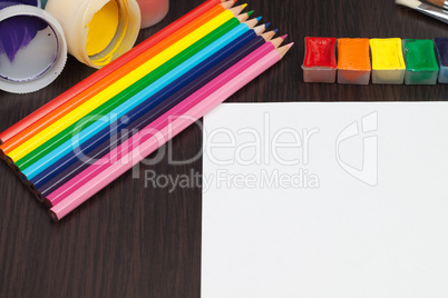 blank sheet of paper with colorful pencils and paints