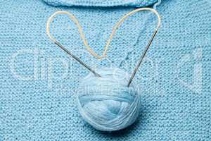 ball of blue wool with steel knitting needles