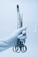hand of surgeon with forceps over blue