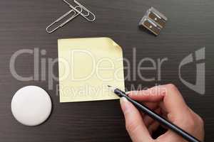 woman writing with pencil on yellow sticker