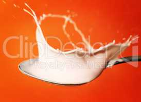 yoghurt splash in the spoon over orange background