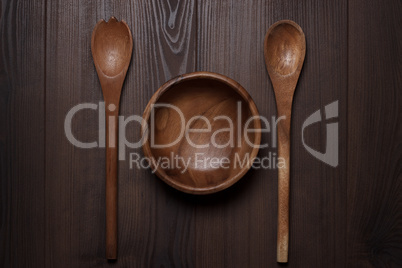 wooden salad bowl and two spoons on the brown table