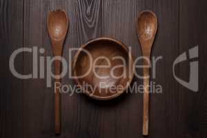 wooden salad bowl and two spoons on the brown table