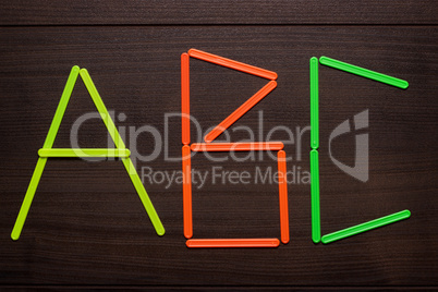 abc formed with counting sticks over wooden background