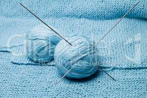 balls of blue wool with steel knitting needles