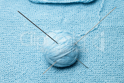 ball of blue wool with steel knitting needles