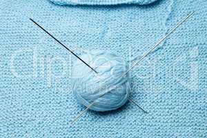 ball of blue wool with steel knitting needles