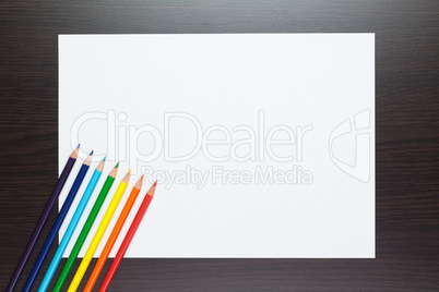 blank sheet of paper on the table with colorful pencils