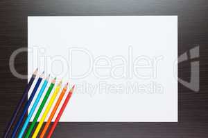 blank sheet of paper on the table with colorful pencils