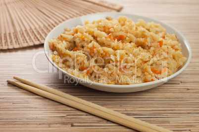 bowl of tasty cooked rice with chopsticks and fan