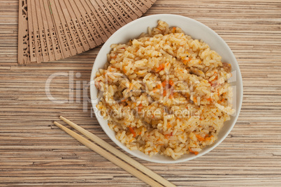 bowl of cooked rice with chopsticks and fan