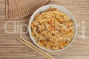 bowl of cooked rice with chopsticks and fan