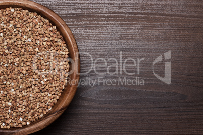 brown wooden bowl full of buckwheat background