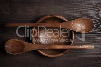 empty salad bowl and two spoons on wooden table