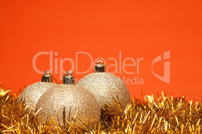 gold shiny christmas balls with tinsel over orange background
