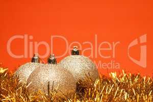 gold shiny christmas balls with tinsel over orange background