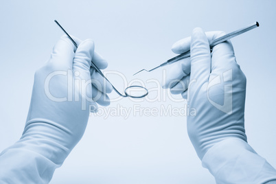 hands of dentist holding his tools during patient examination