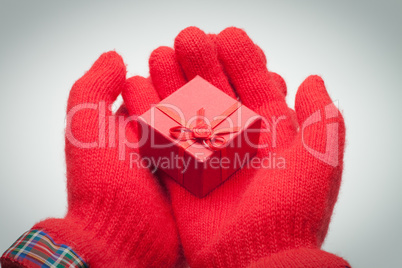 hands giving red box with present over grey background
