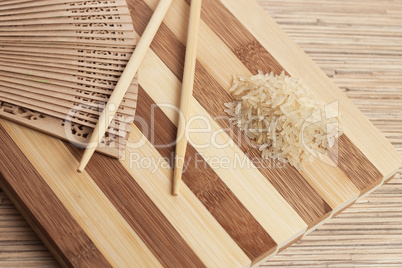 raw rice ready to be cooked on the breadboard with chopsticks