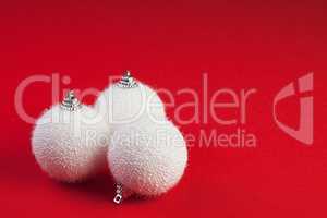 three white christmas balls over red background