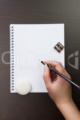 woman writing with pencil on notebook in the office