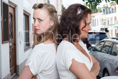 Zwei Frauen stehen Rücken an Rücken auf einer Stadtstraße
