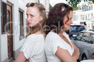 Zwei Frauen stehen Rücken an Rücken auf einer Stadtstraße