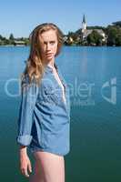 Frau im Jeanshemd stehend vor einem ruhigen See