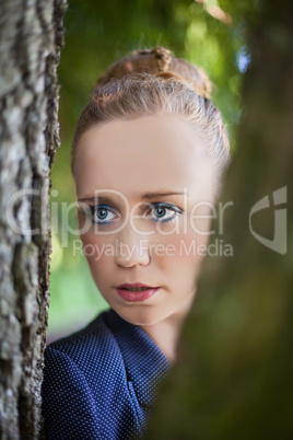 Junge Frau schaut durch Baum-Stämme