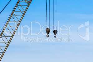 Pair of industrial crane hoists on cables near truss