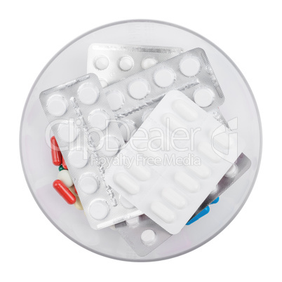 Pills lying blister packed in a bowl. Isolated on white background