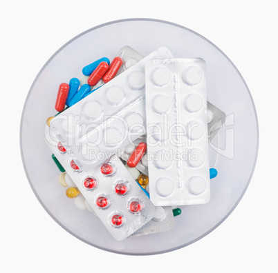 Pills lying blister packed in a bowl. Isolated on white background