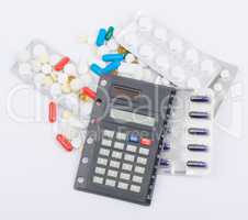 Tablets with capsules in blister packs and calculator lying on top