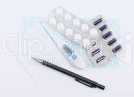 Pills capsules in blister packs with white paper sheet and ballpoint pen