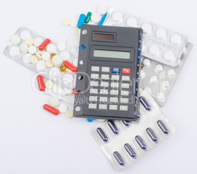 Tablets with capsules in blister packs and calculator lying on top